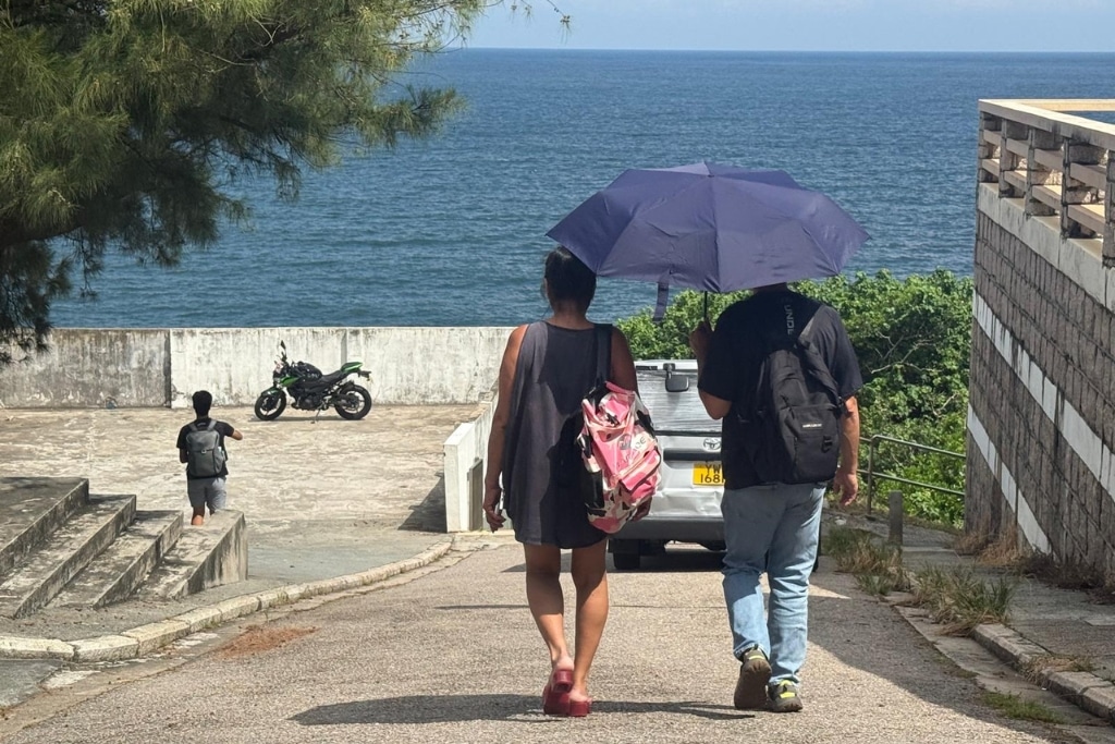 A man and a woman protect themselves from the sun in Hong Kong.