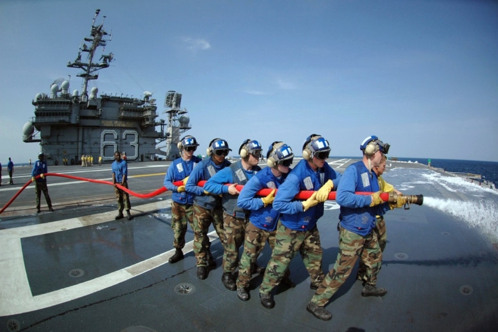 US Navy (USN) Air Department personnel wash Aqueous Film Forming Foam (AFFF) off the flight deck of the USN Aircraft Carrier USS KITTY HAWK (CV 63) while participating in the ship's firefighting drills.